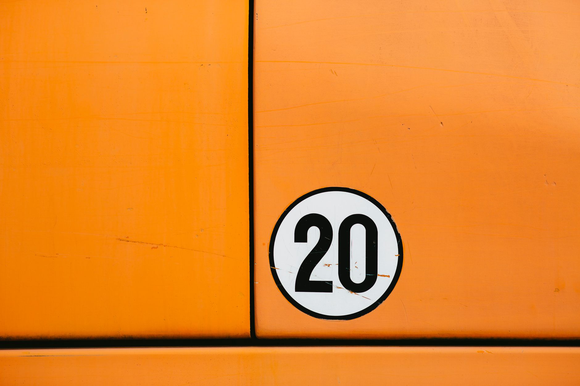 Close-up of a vintage orange vehicle door featuring a bold number 20 in a circle.