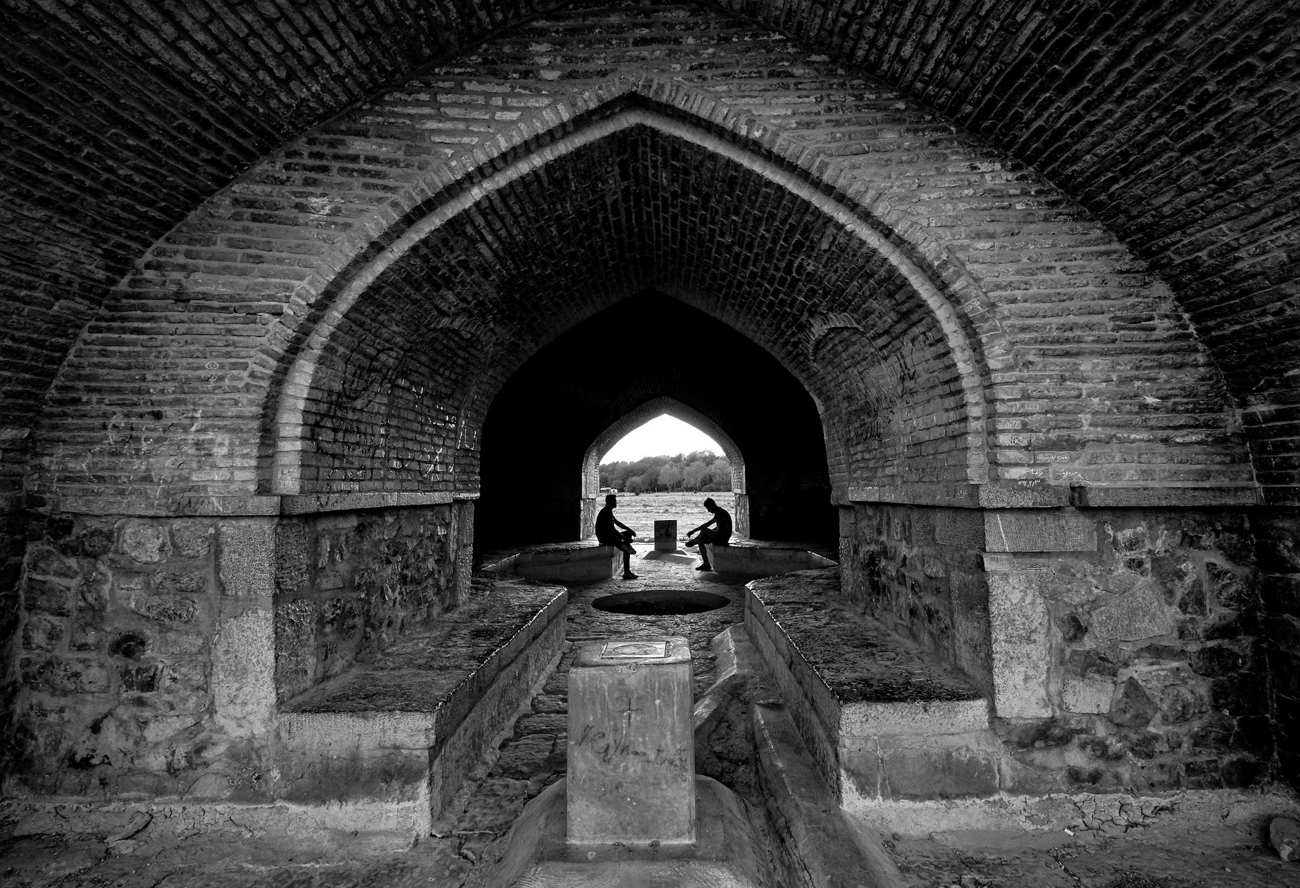 Black and white photo of Si-o-se-pol Bridge passage in Isfahan, Iran, highlighting its arched architecture.