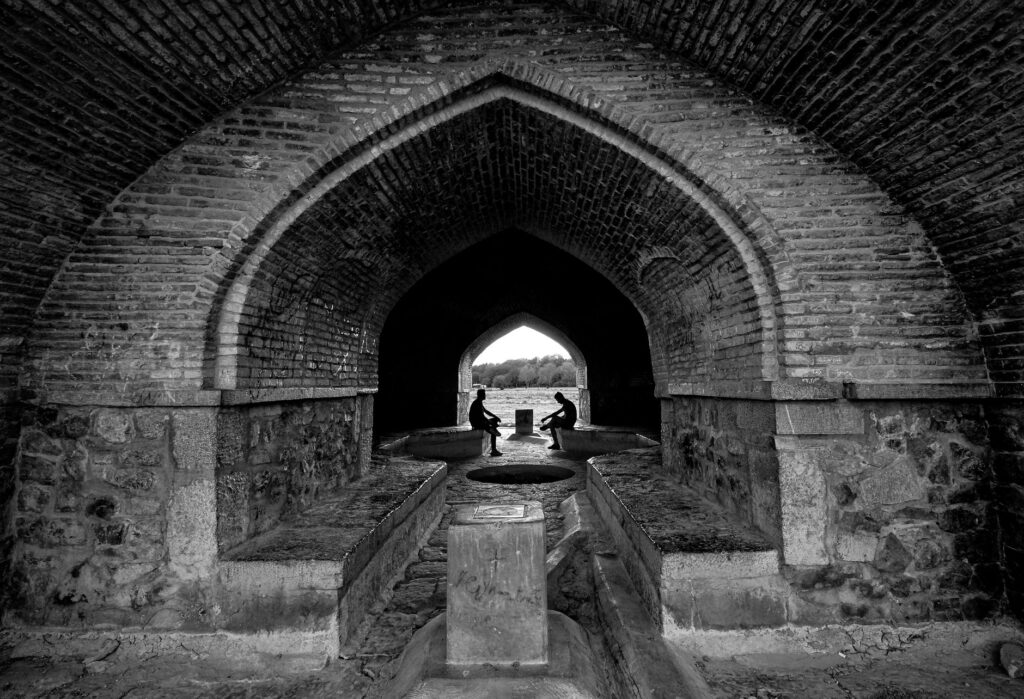 Black and white photo of Si-o-se-pol Bridge passage in Isfahan, Iran, highlighting its arched architecture.