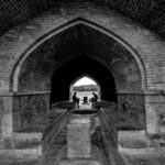 Black and white photo of Si-o-se-pol Bridge passage in Isfahan, Iran, highlighting its arched architecture.