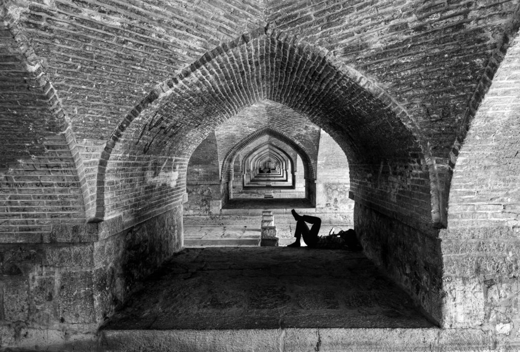 Relaxing under historic arches of the Si-o-se-pol Bridge, capturing architectural beauty in Esfahan.