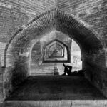 Relaxing under historic arches of the Si-o-se-pol Bridge, capturing architectural beauty in Esfahan.