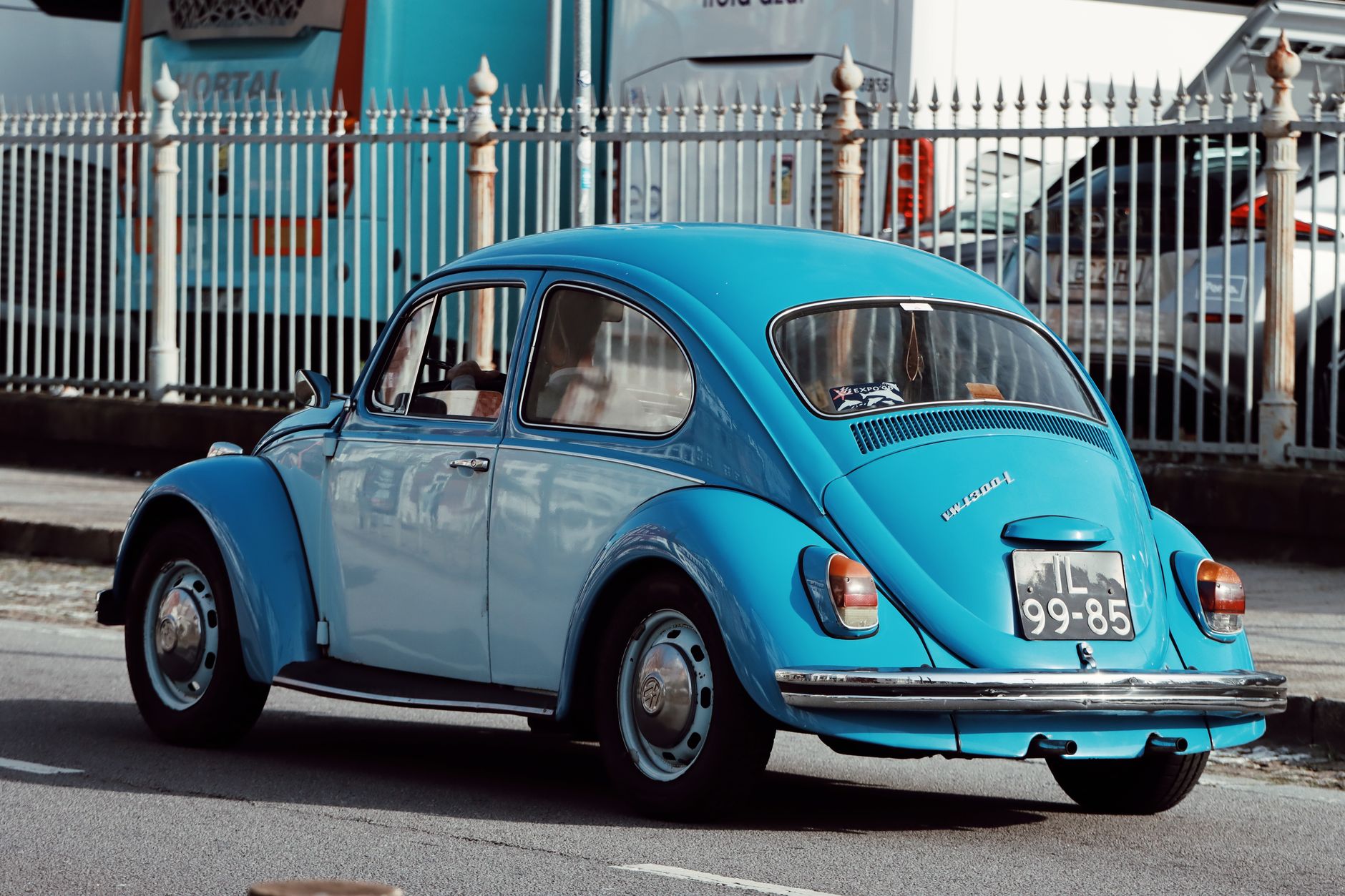 Classic blue Volkswagen Beetle driving on a street in Porto, Portugal, a glimpse of automotive nostalgia.
