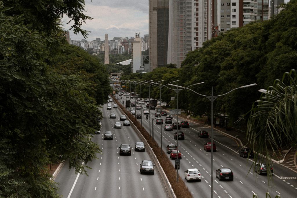 View of a bustling highway surrounded by lush greenery and modern architecture in São Paulo, Brazil.