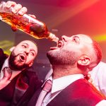 Vibrant nightlife party with men celebrating and pouring drinks.