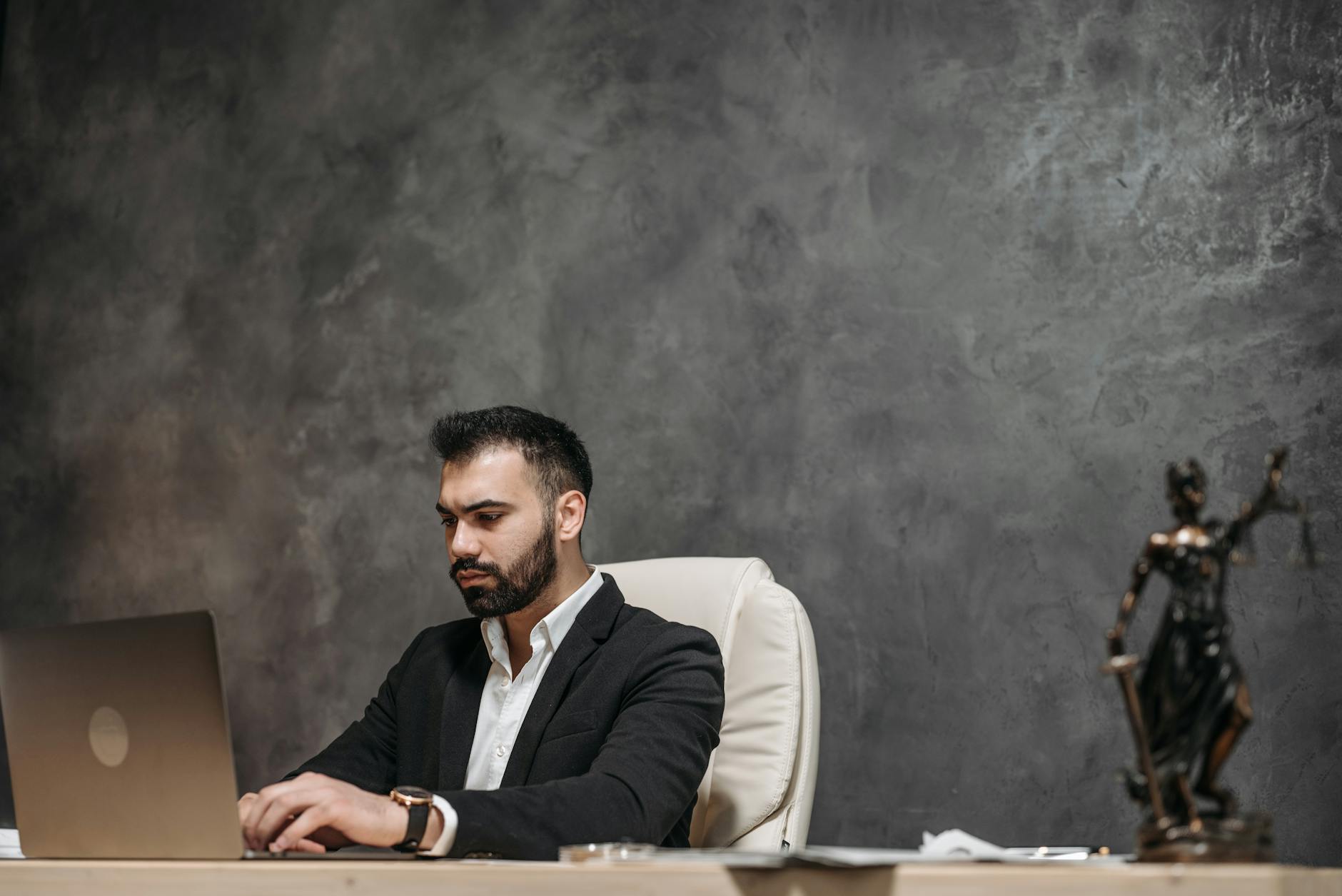 Focused professional man in an office environment working on a laptop.