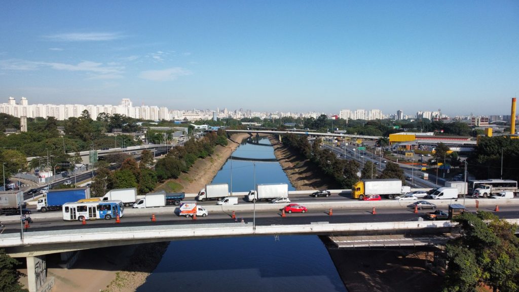 Aerial view of São Paulo cityscape with a busy highway, river, and urban landscape on a clear day.