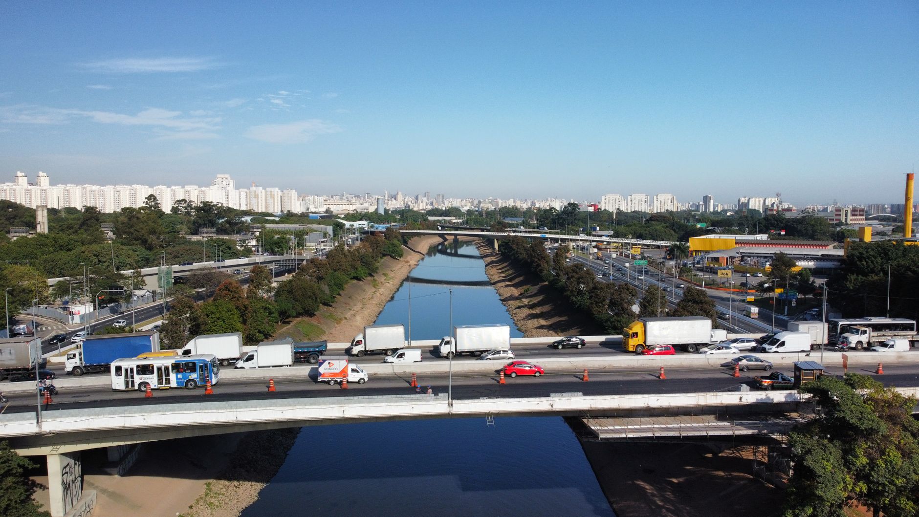 Aerial view of São Paulo cityscape with a busy highway, river, and urban landscape on a clear day.