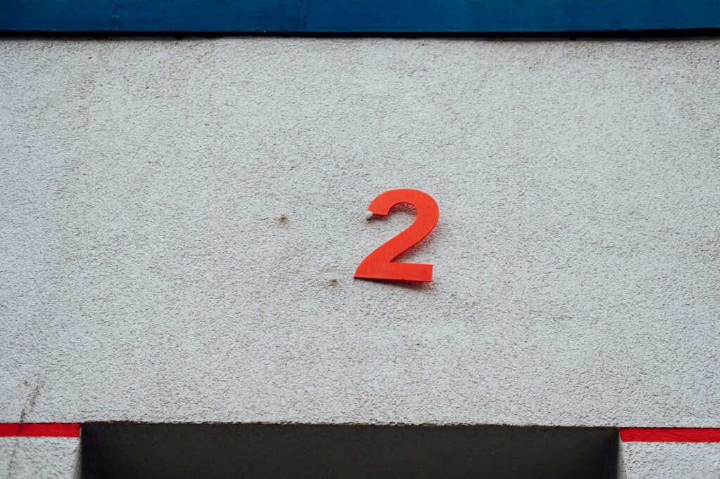 A simple red number 2 on a textured concrete wall with minimalistic design elements.