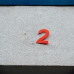 A simple red number 2 on a textured concrete wall with minimalistic design elements.