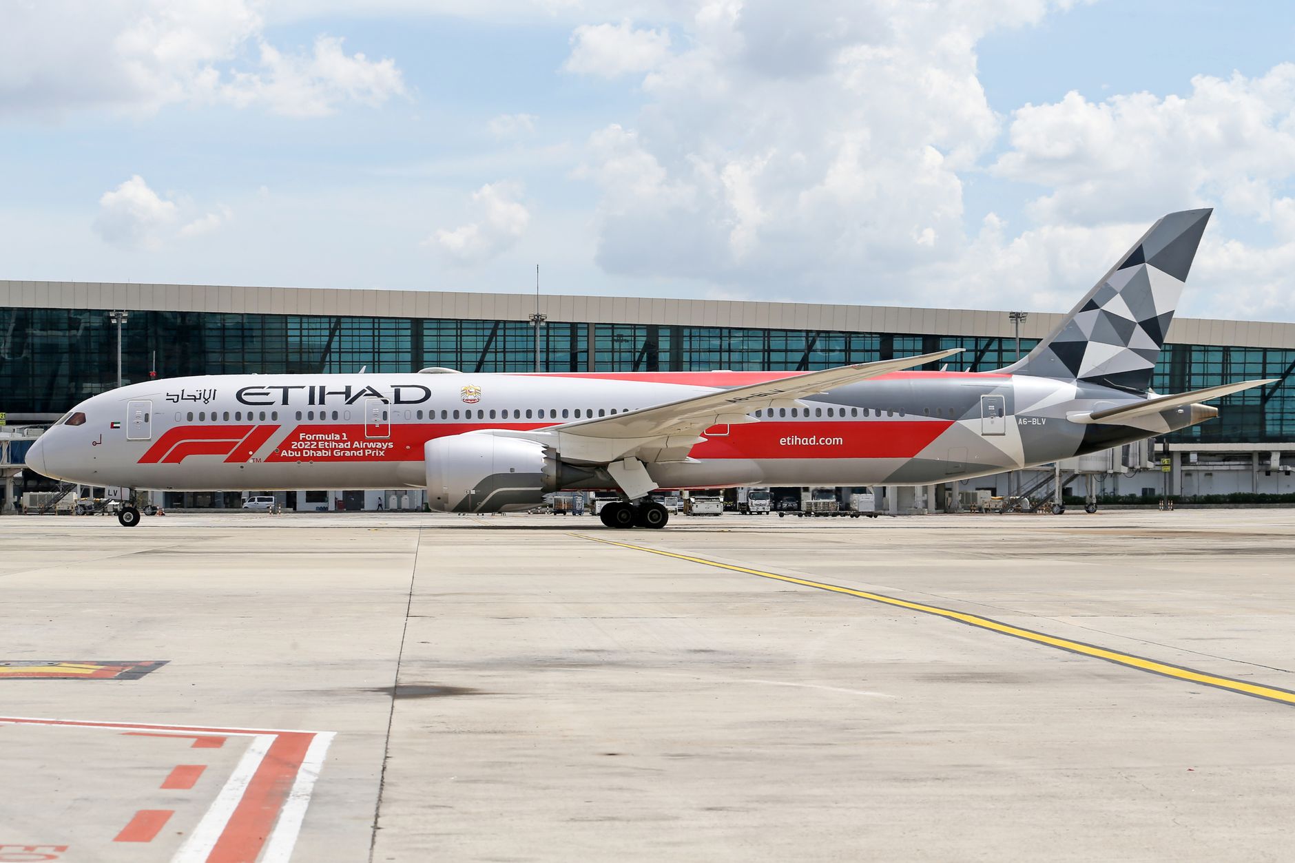 Etihad Airways Boeing 787 with Formula 1 livery parked at a modern airport.