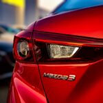 Stunning close-up of the tail light of a red Mazda 3 showcasing sleek design and vibrant color.