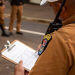 Close-up of a police officer writing on a clipboard outdoors in Londrina, Brazil.