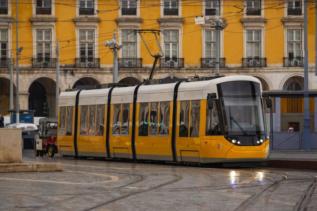 Bright yellow tram passing through the historic Commerce Square in Lisbon, Portugal.