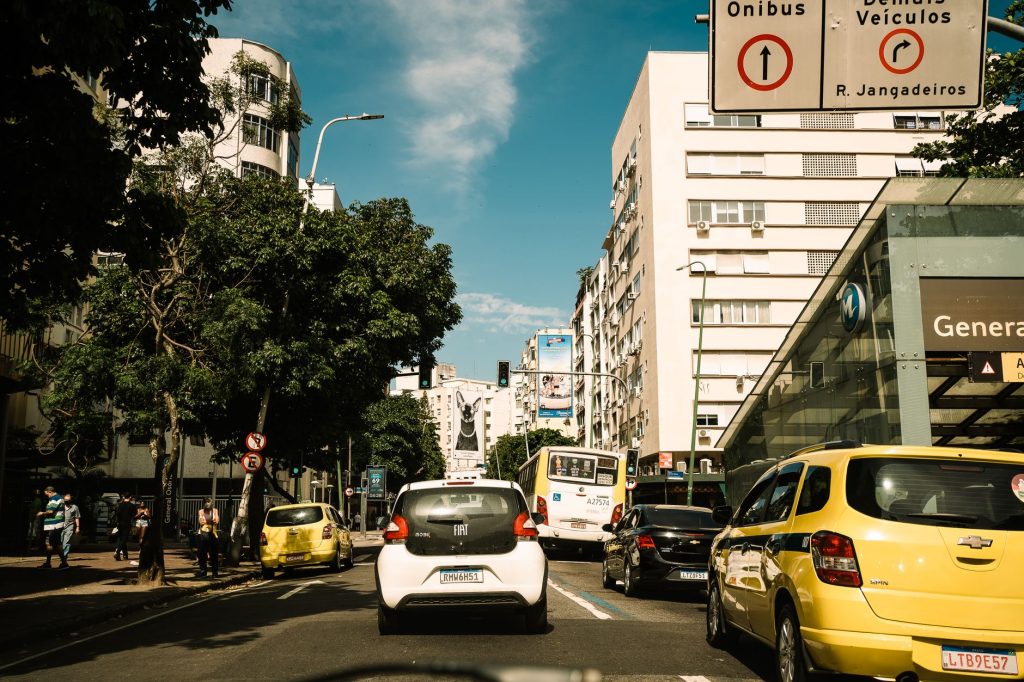 Capture of a lively street in Rio de Janeiro, featuring traffic and pedestrians on a sunny day.