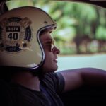 Side profile of a man driving, wearing a Ruta 40 helmet and sunglasses.