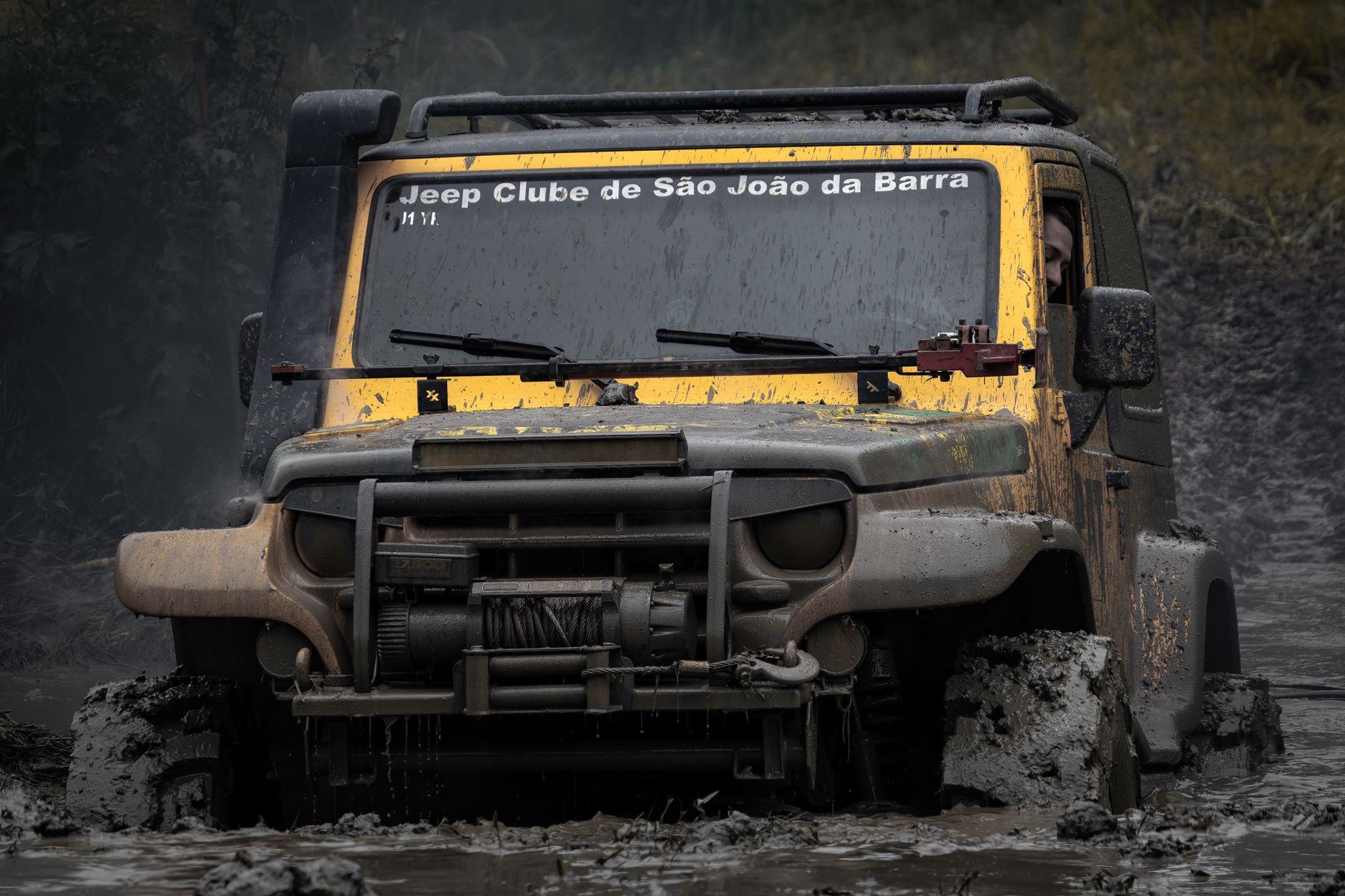 A rugged Jeep navigates through thick mud, showcasing its off-road capabilities.
