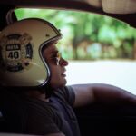 Man wearing a Ruta 40 helmet driving a car, looking into the distance.