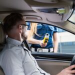 Officer administering a breathalyzer test to a driver during a roadside check for safety.