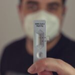 A person holding a negative COVID-19 antigen test with a face mask on, focused on the test result.