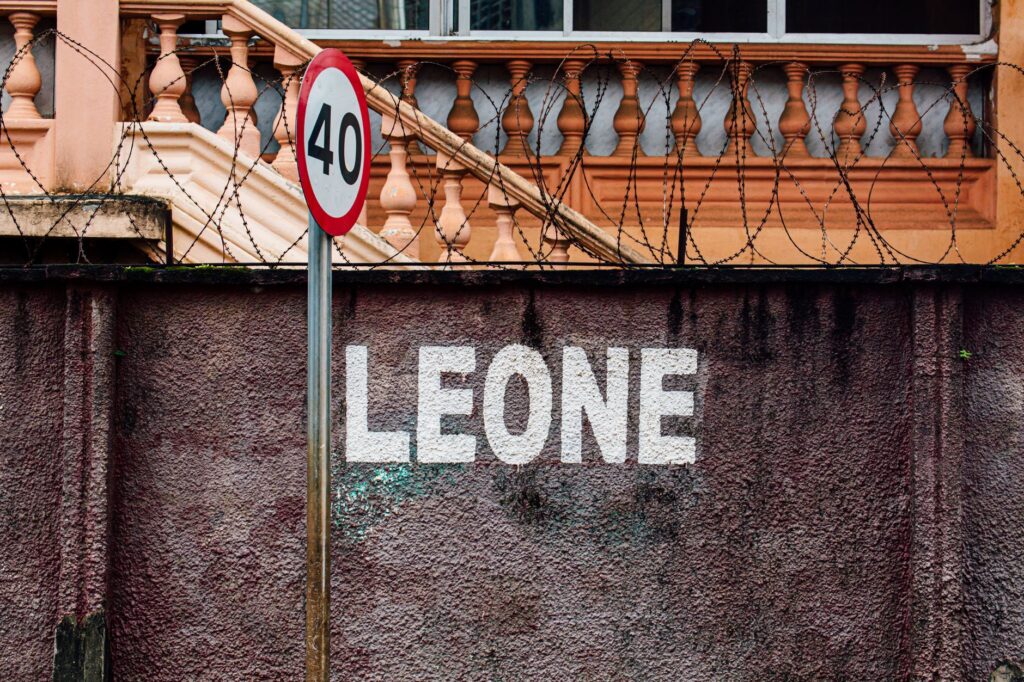 Photo of a 40 speed limit sign on a wall with 'LEONE' text and barbed wire.