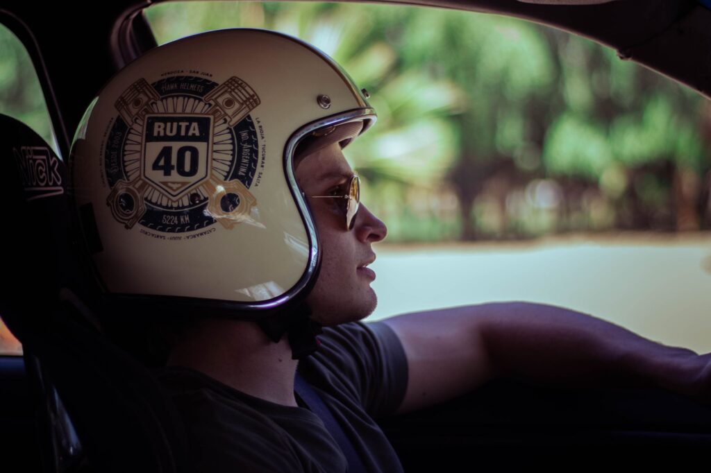 Side profile of a man driving, wearing a Ruta 40 helmet and sunglasses.