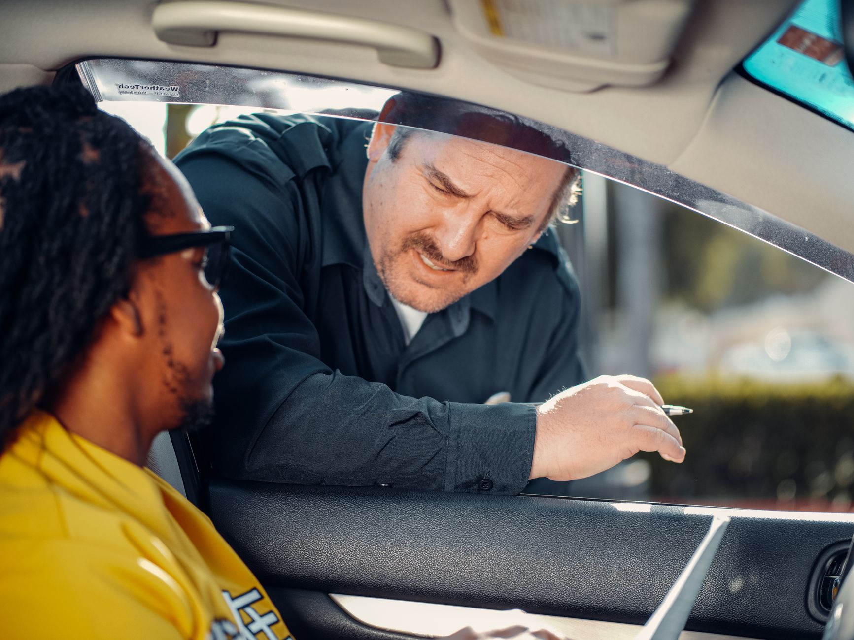 A police officer interacts with a driver through a car window, emphasizing law enforcement and public safety.