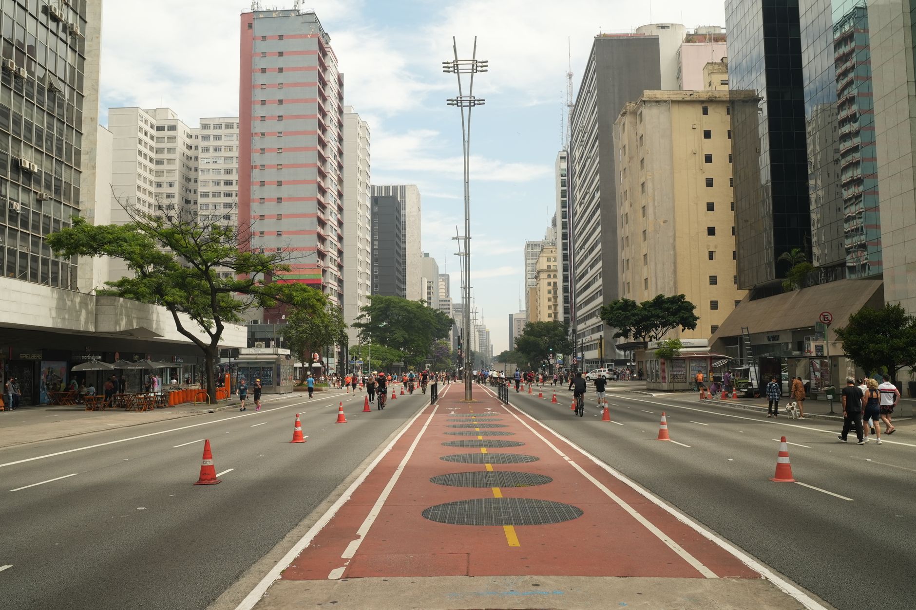 A vibrant scene captures the dynamic energy of Paulista Avenue in São Paulo on a sunny day.