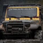 A rugged Jeep navigates through thick mud, showcasing its off-road capabilities.