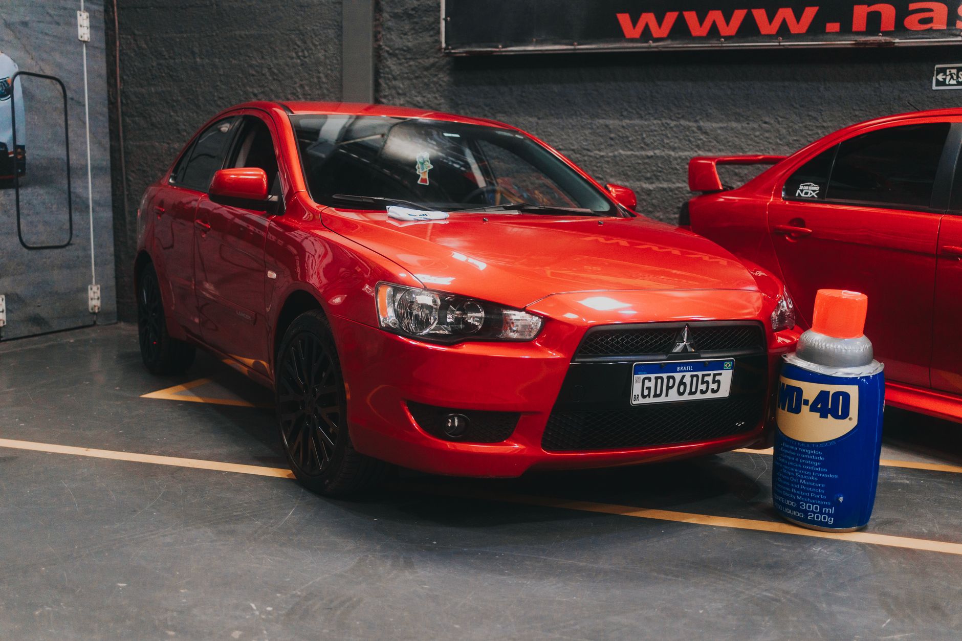 Bright red car parked indoors near a WD-40 can, showcasing a shiny modern vehicle in a garage.