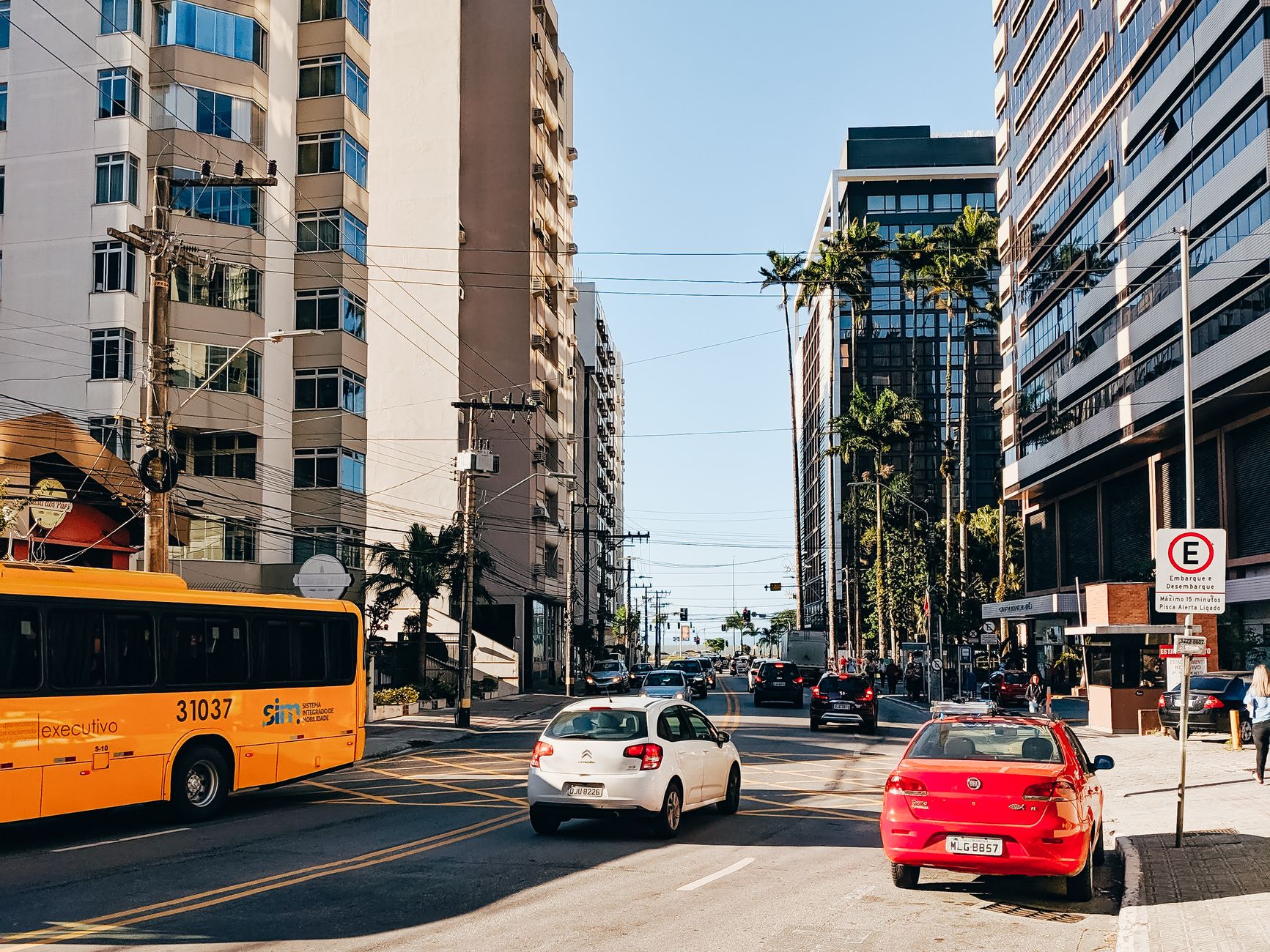 A vibrant city street featuring buses and cars amid tall modern buildings during daytime.