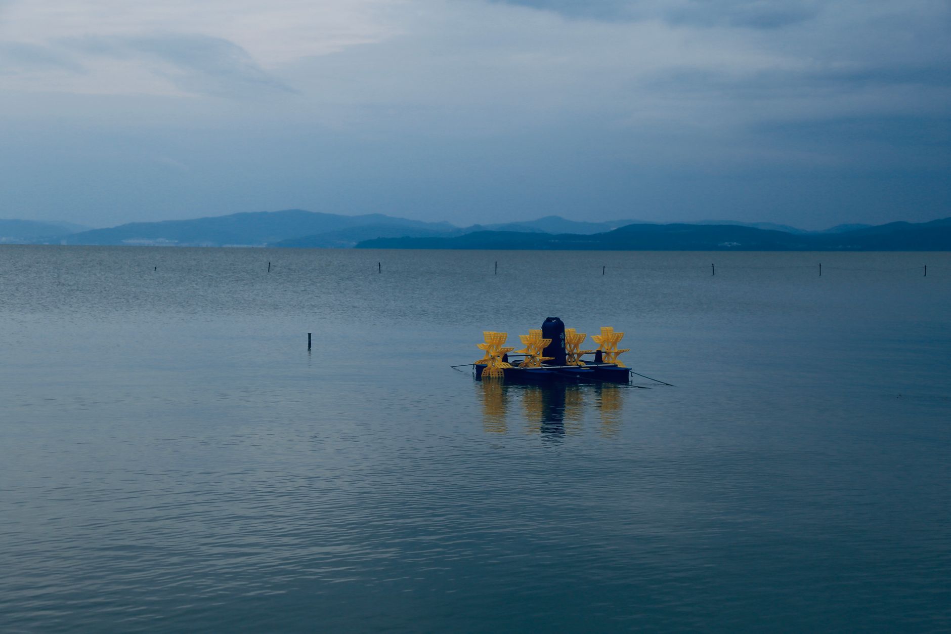 A single boat moored in a calm bay during twilight, evoking a peaceful and moody atmosphere.