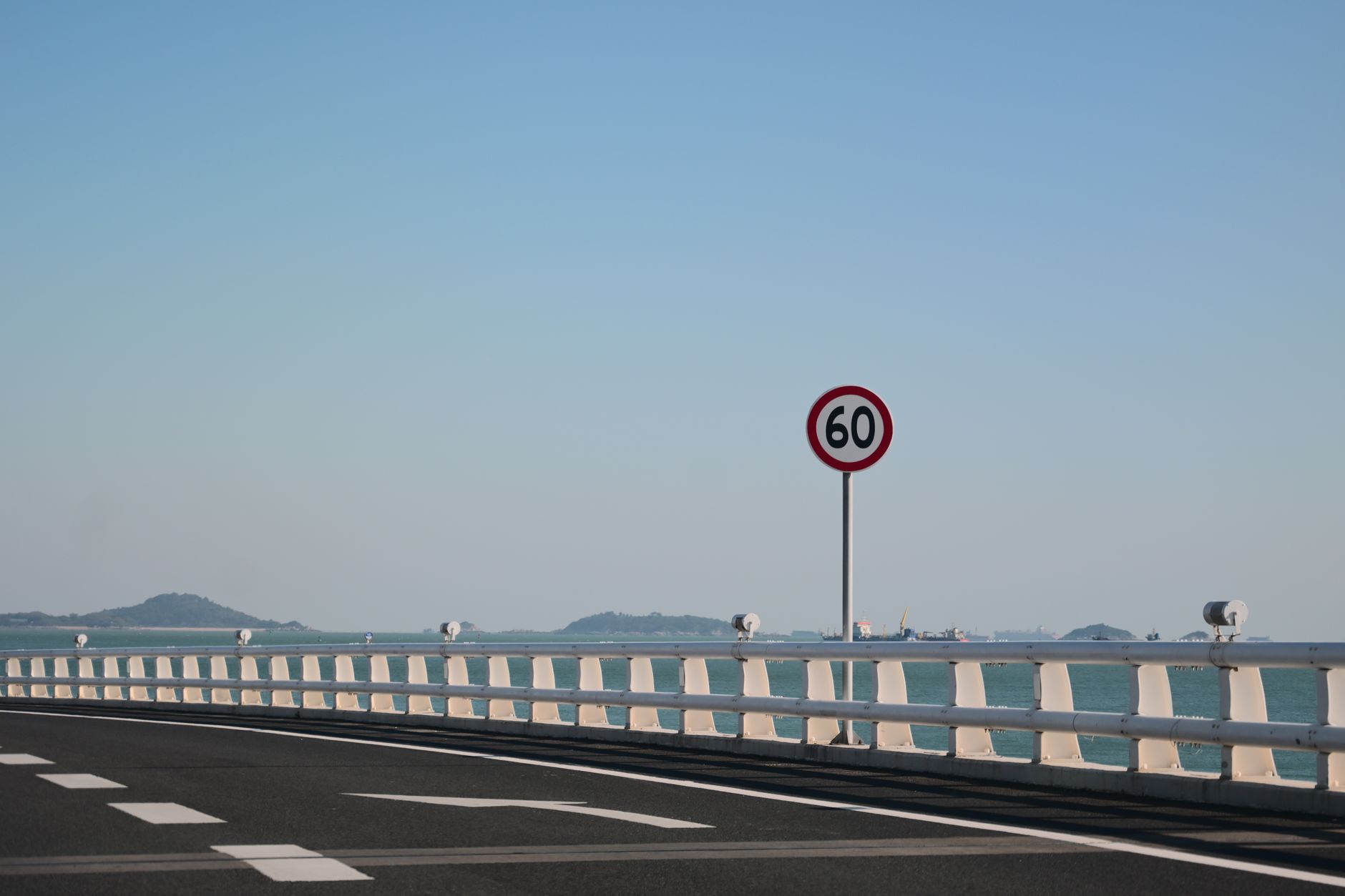Calm coastal road on a bridge with a speed limit of 60 km/h and distant islands.