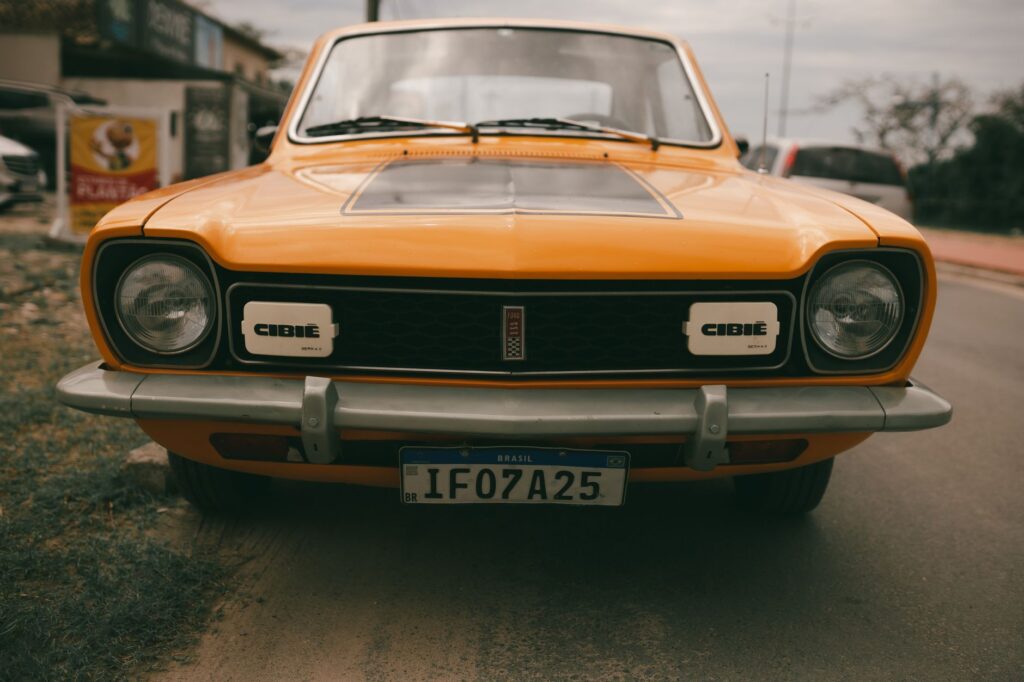 Front view of a vintage orange Ford Corcel convertible car parked on a road with Brazilian license plate.