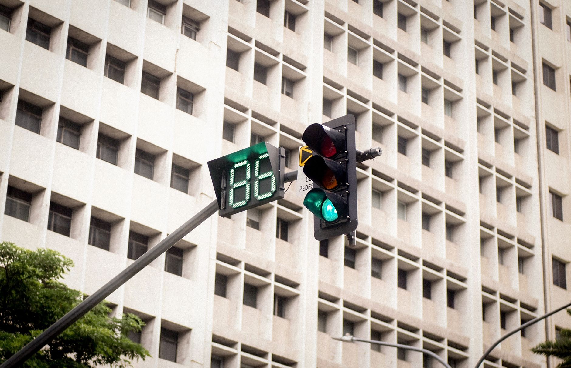 Green traffic light with countdown timer in city setting.