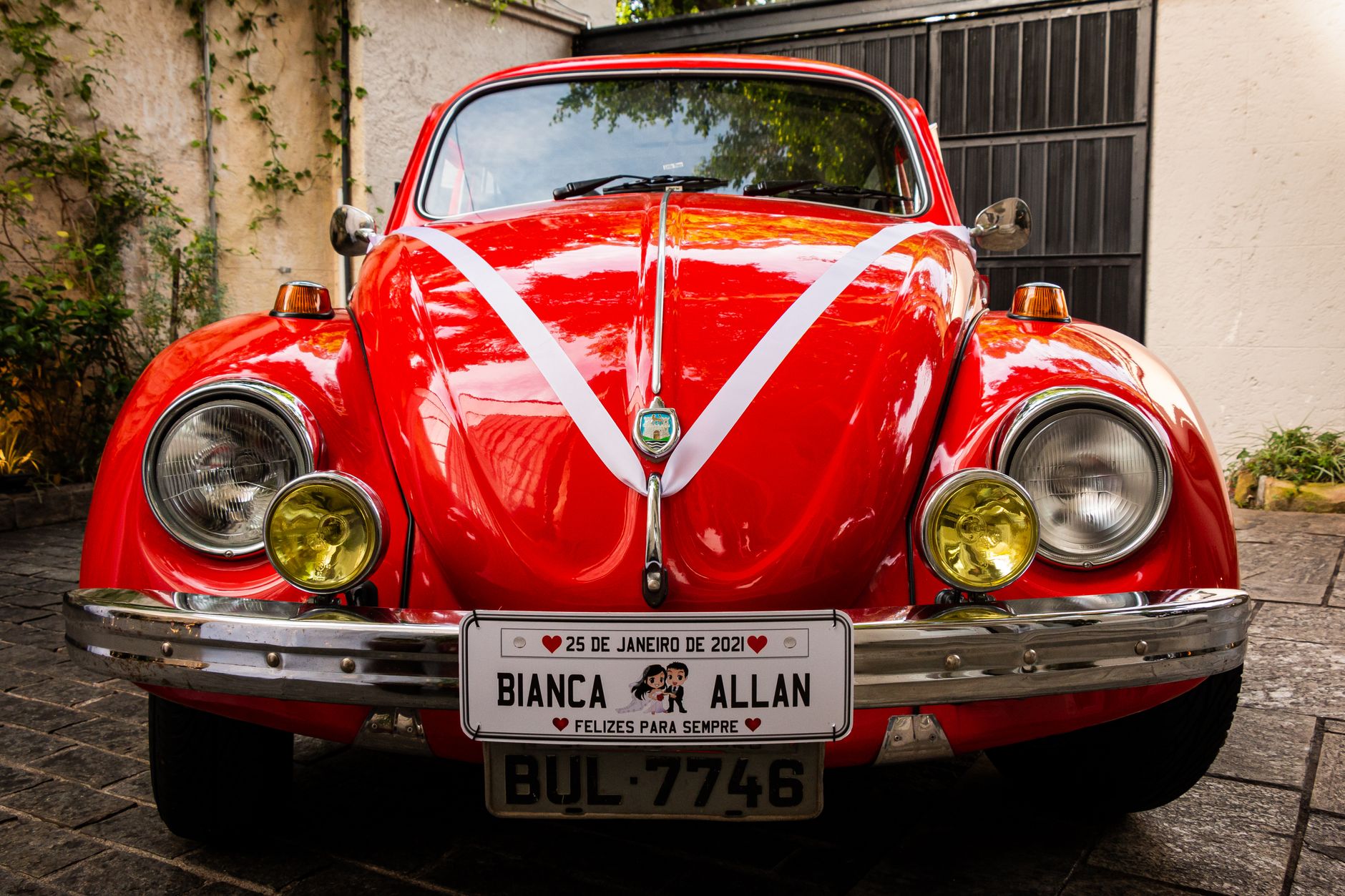Vintage red VW Beetle decorated for wedding, showcasing classic design and personalized plate.