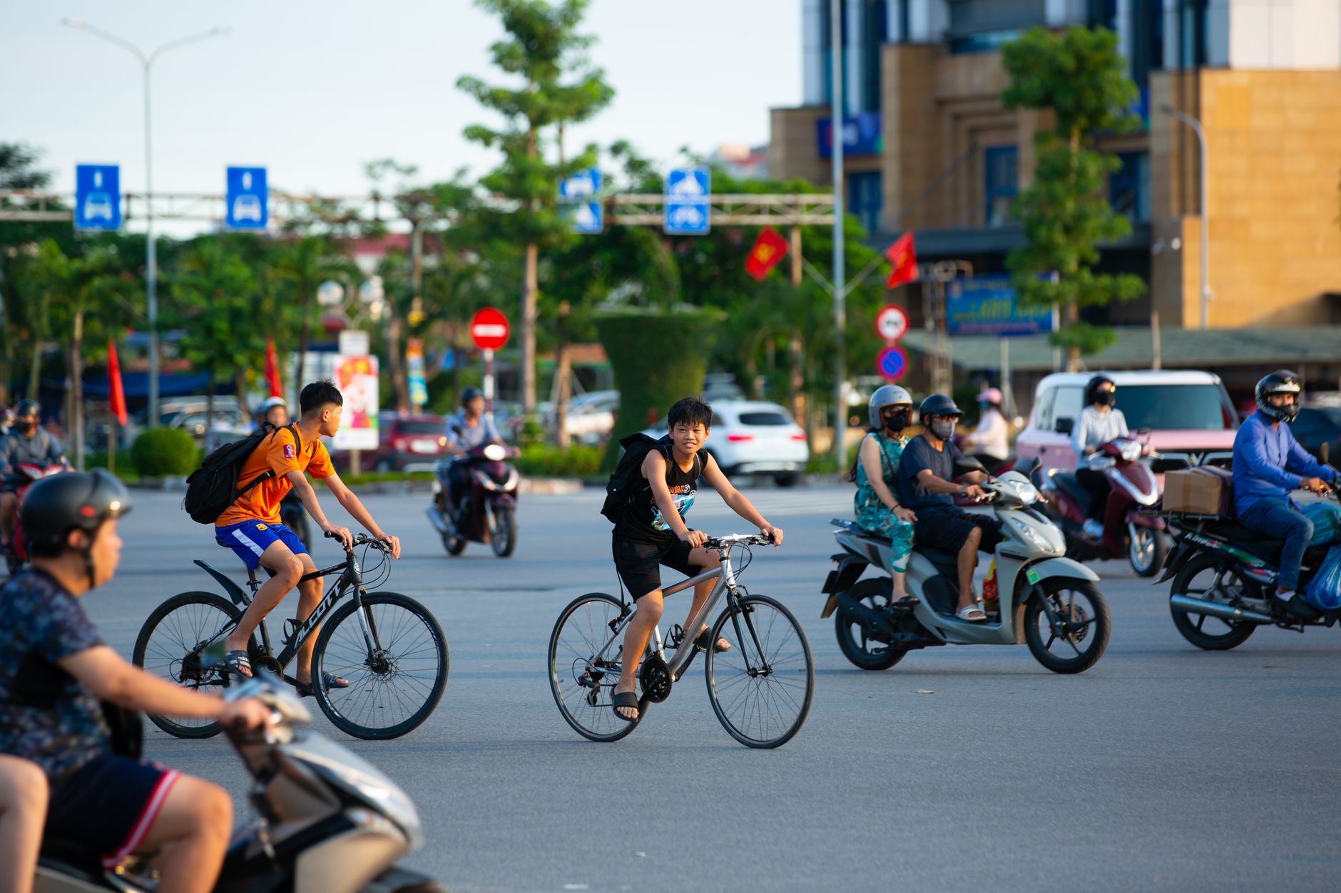 Cyclists and motorcyclists navigate a busy urban intersection on a sunny day, showcasing city life.