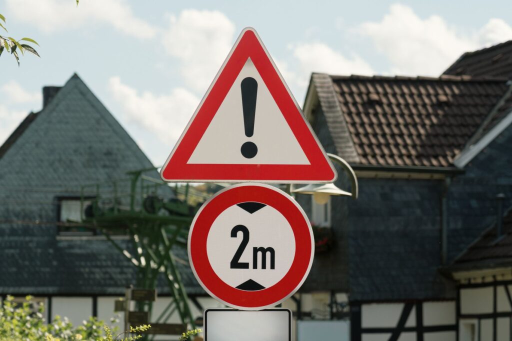 Traffic signs in a rural German village indicating warning and a 2m distance restriction.