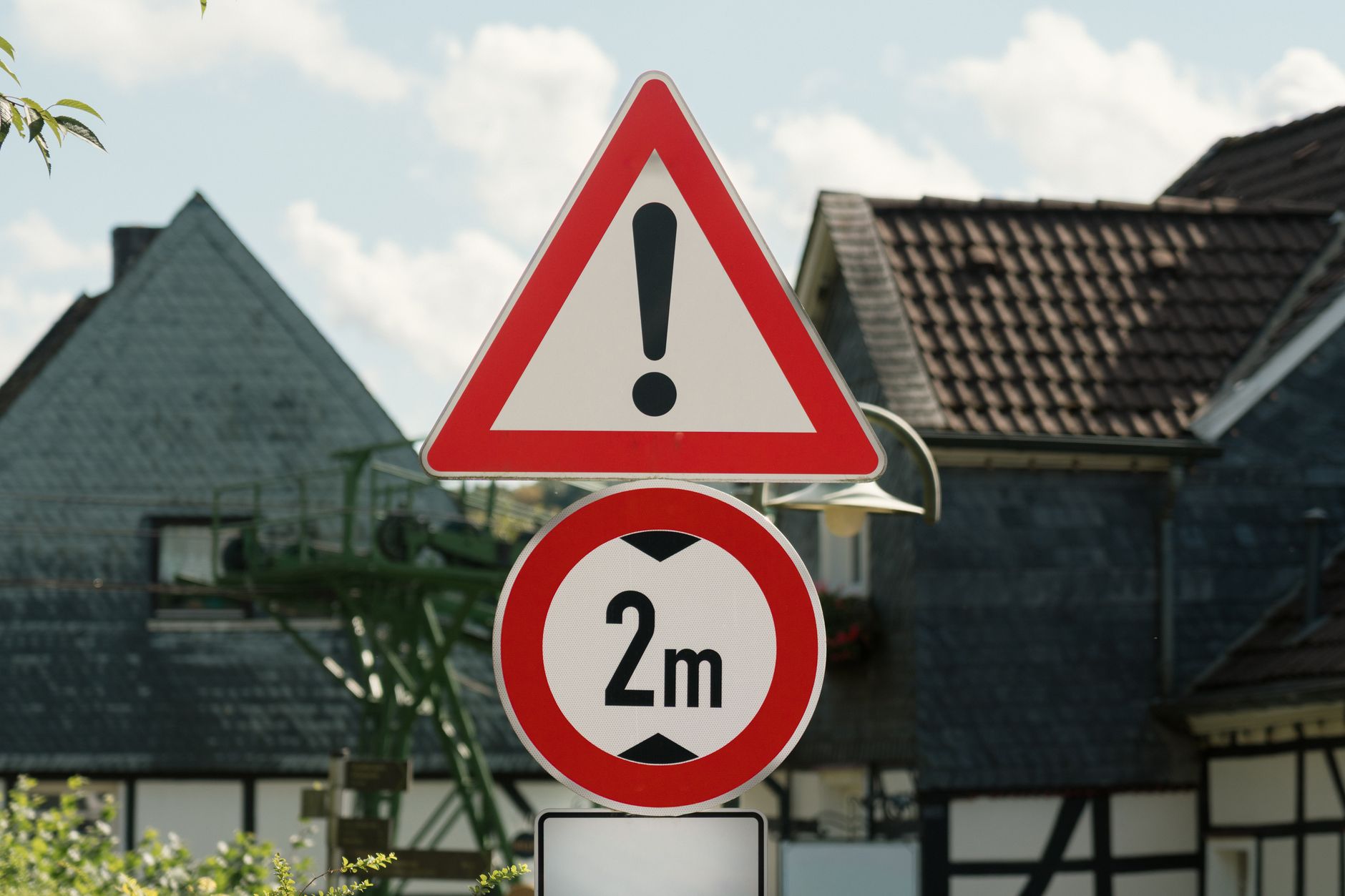 Traffic signs in a rural German village indicating warning and a 2m distance restriction.