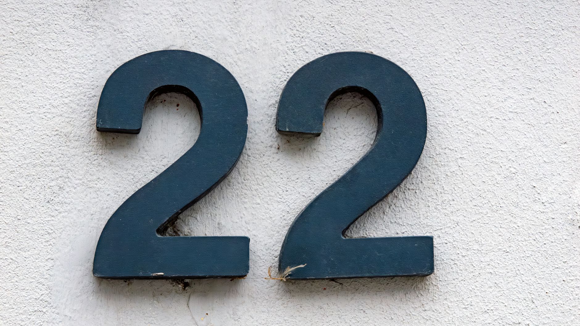 A close-up of the number 22 mounted on a textured white wall, ideal for number-related projects.