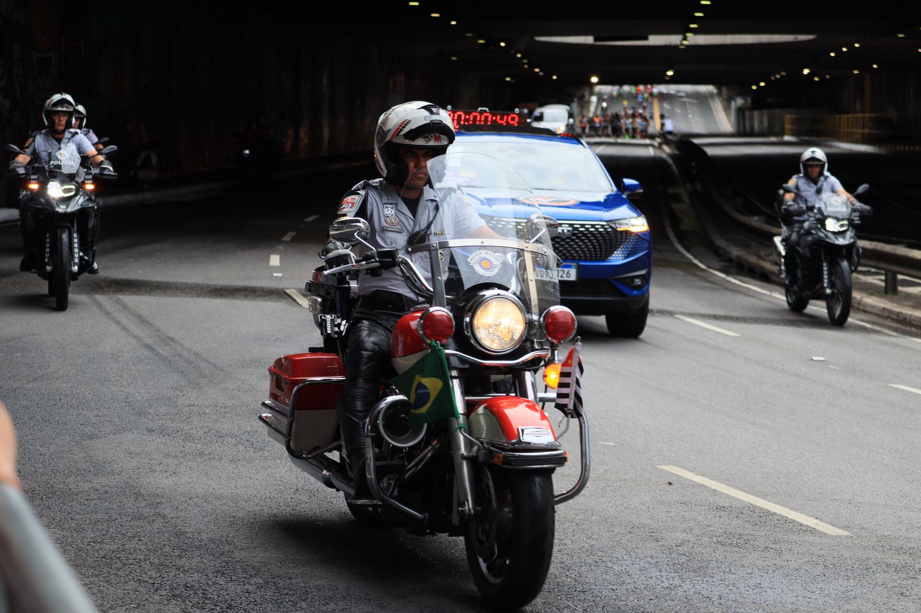 A police motorcycle team escorts vehicles through a city tunnel.