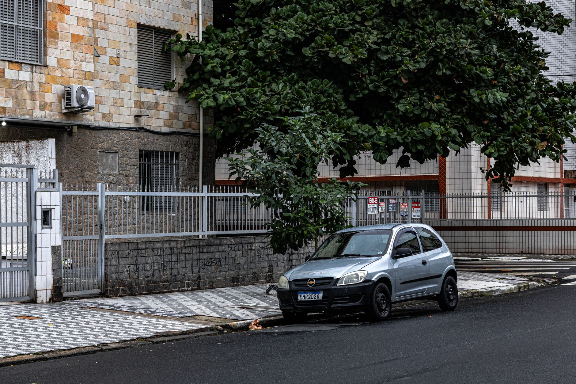 Quiet urban street in Praia Grande, São Paulo with a parked car and residential buildings.