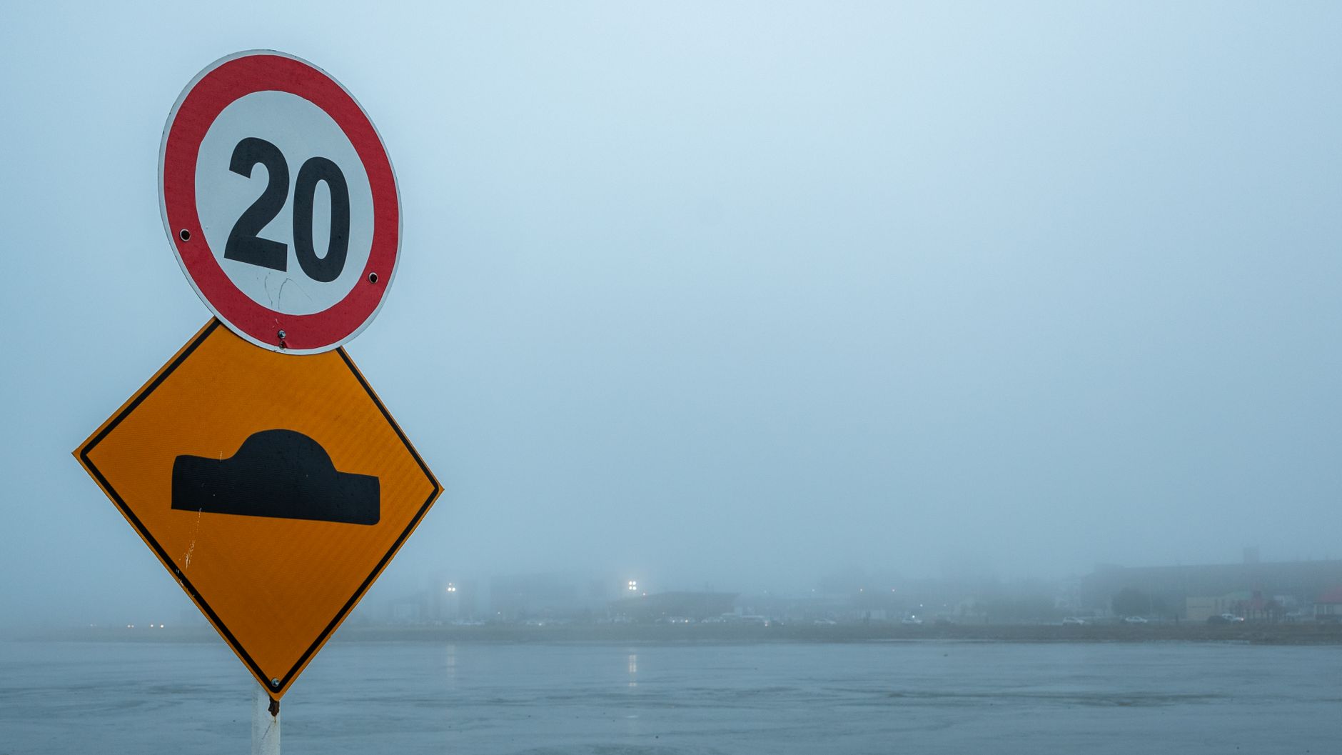 A speed limit and bump sign in the foggy streets of Ushuaia, Argentina.